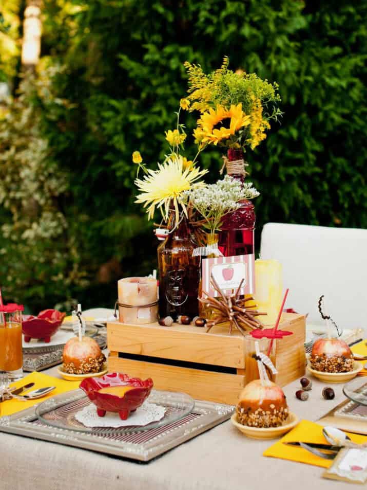 tablescape set up outside with sunflowers, wildflowers, and candy apples.