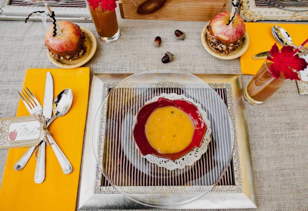 fall themed place setting with DIY frame placemat, clear dinner plate, and red soup bowl.