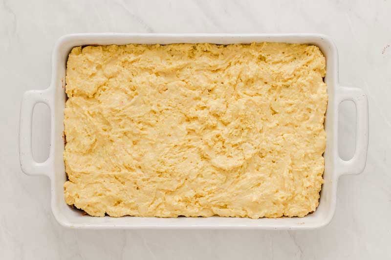 white casserole dish with cornbread mixture ready to bake.