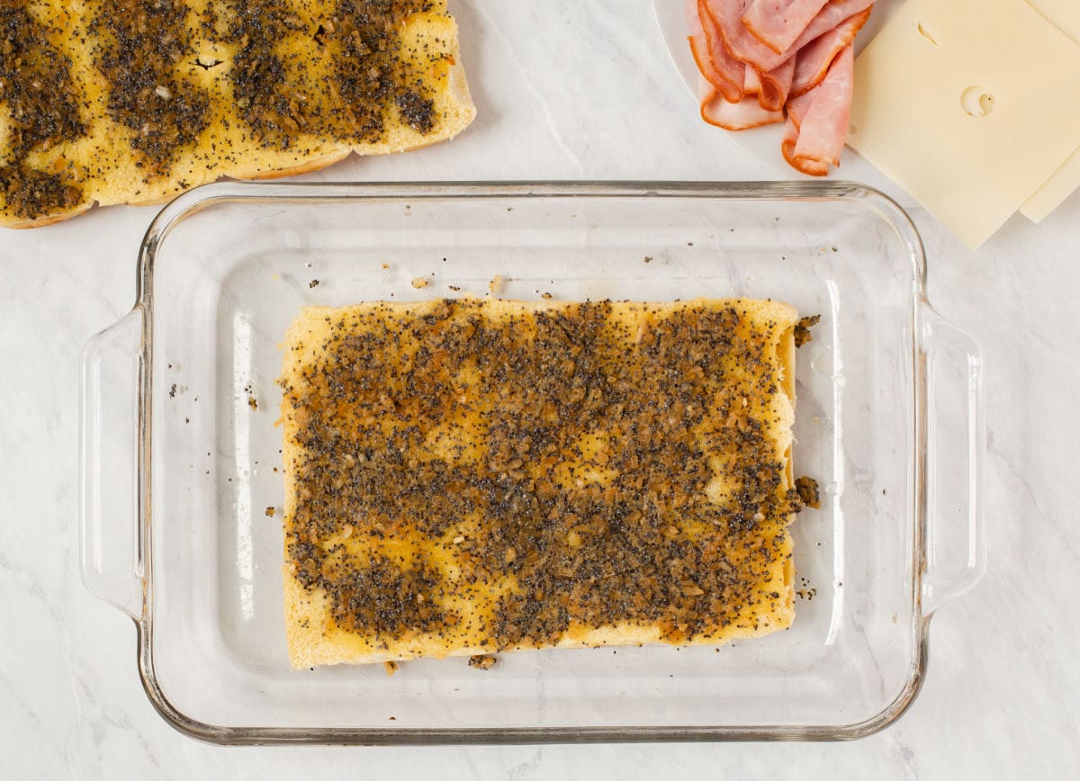 A sheet of party rolls in baking dish with butter mixture on top.