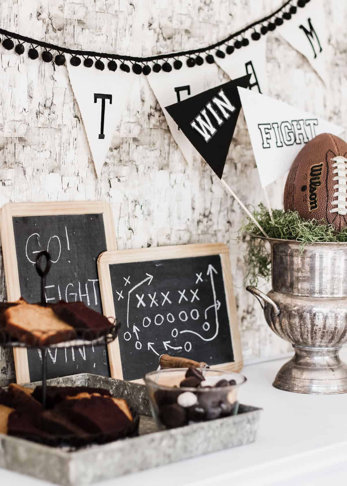 table with baked goods, chalkboards, and football trophy decor for a party.