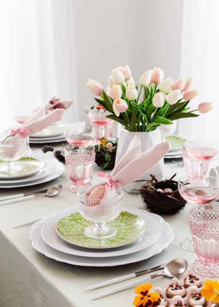 Easter tablescape with green and pink decor and napkins folded like bunny ears.