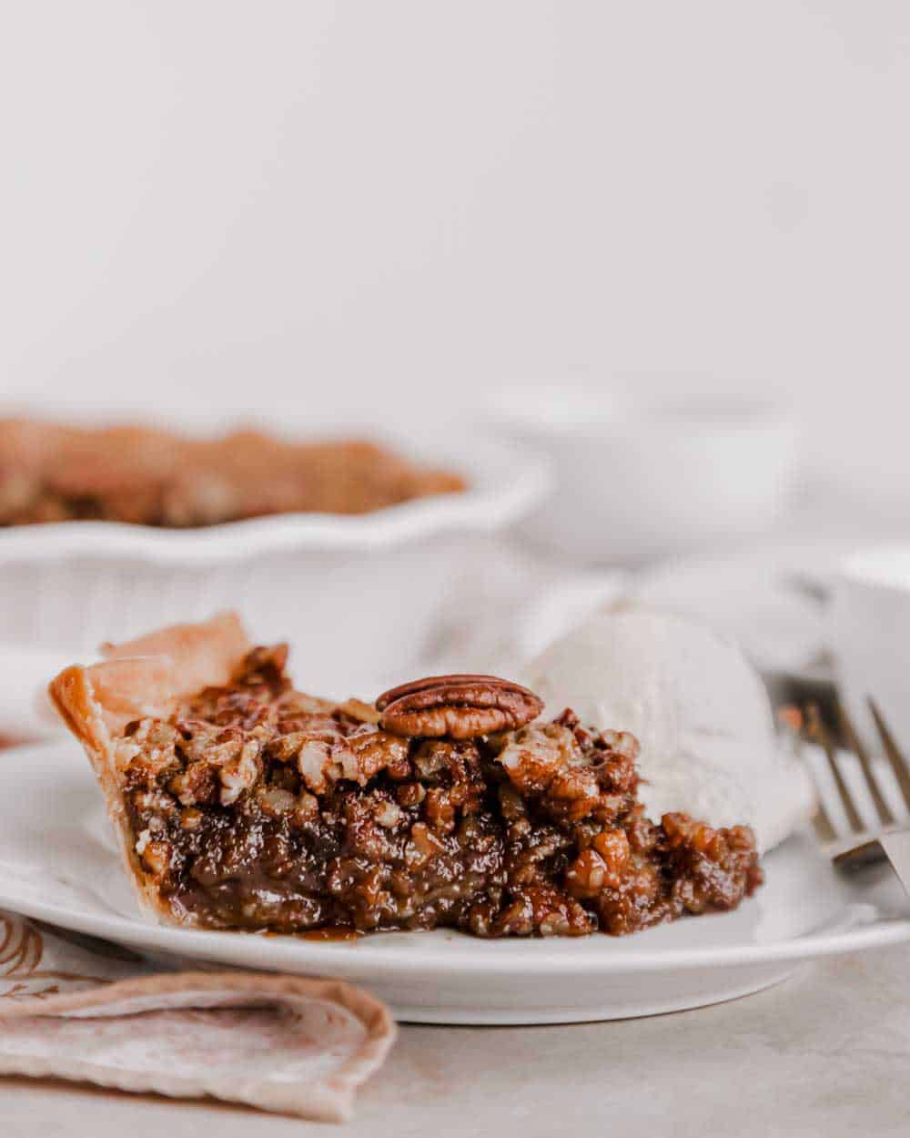 pecan pie slice on white plate with scoop of ice cream.