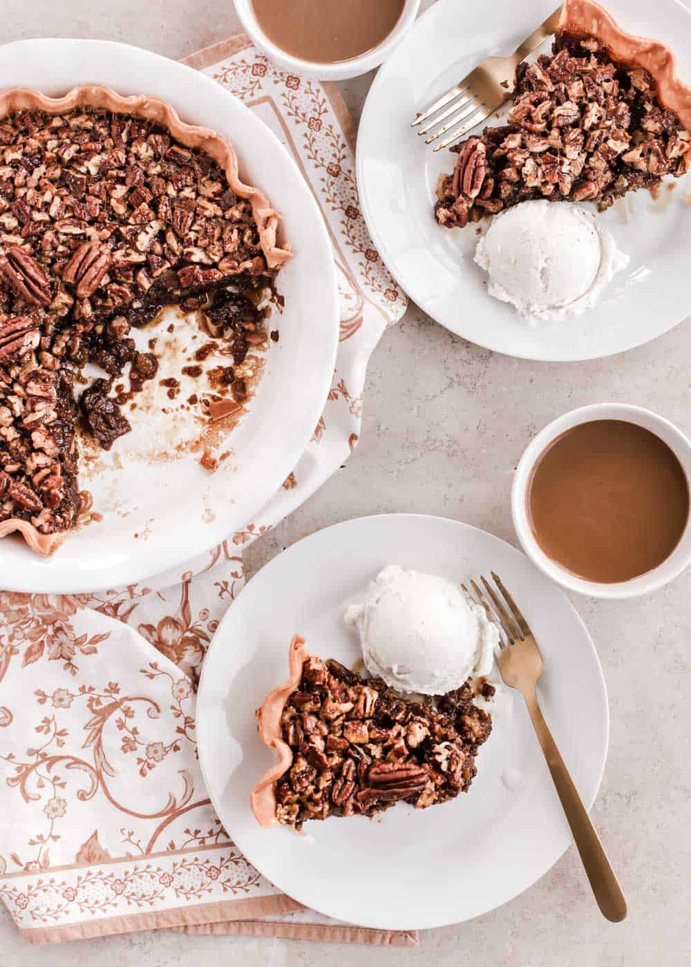 pecan pie with two slices on white plates with ice cream.