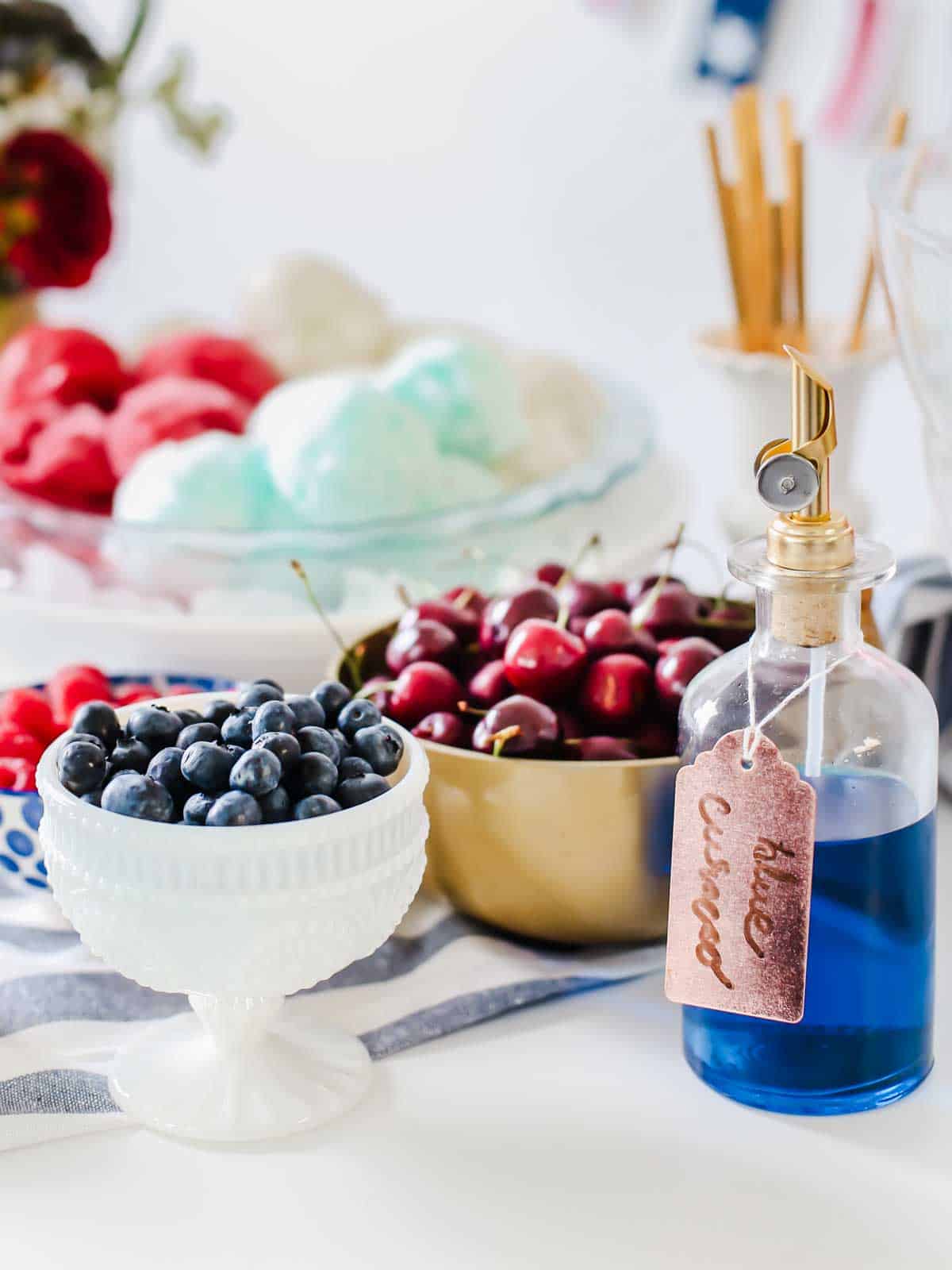 fresh berries in bowls on white table, with ice cream scoops in background.