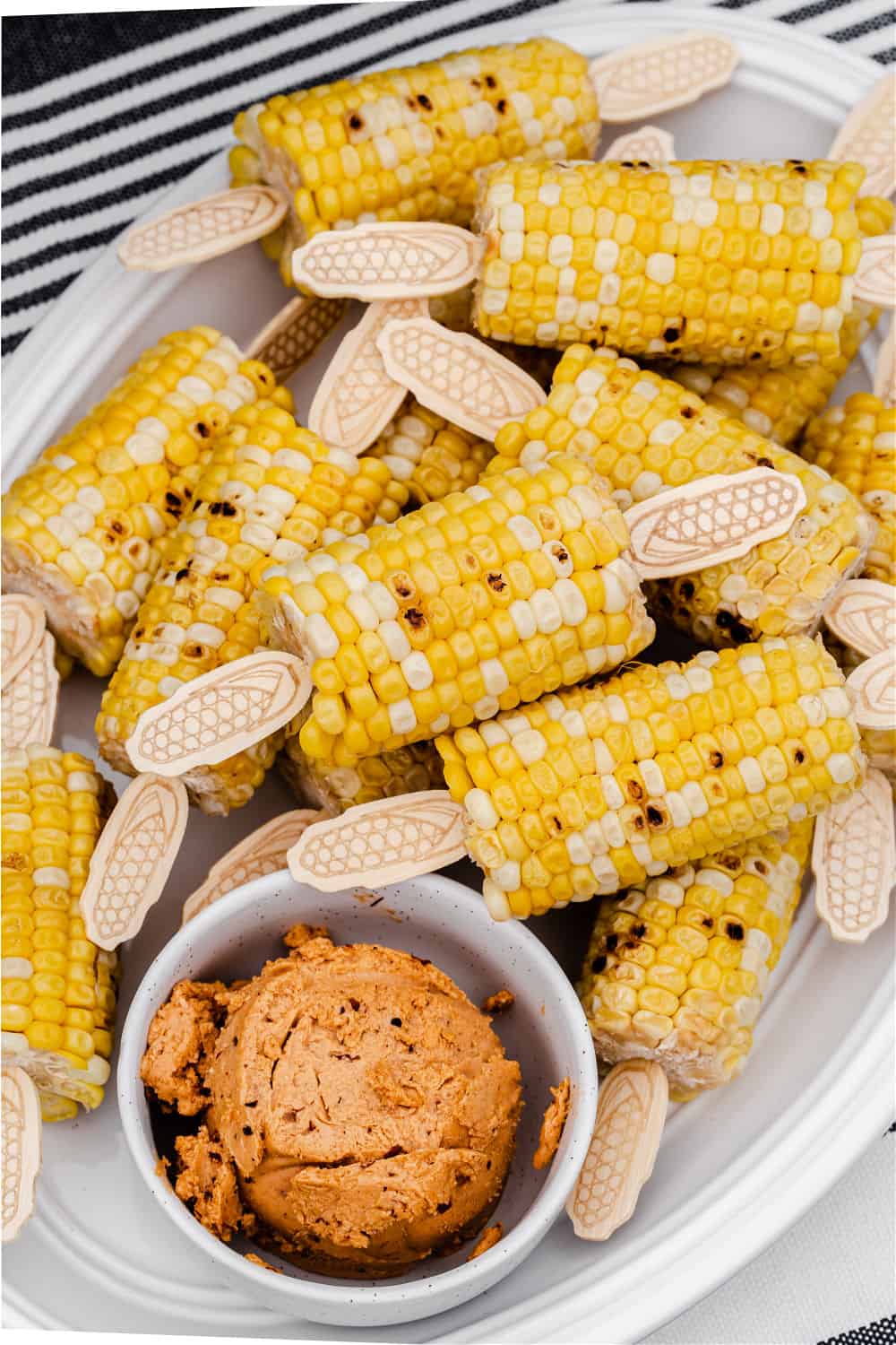 corn on the cob with flavored butter, on white plate