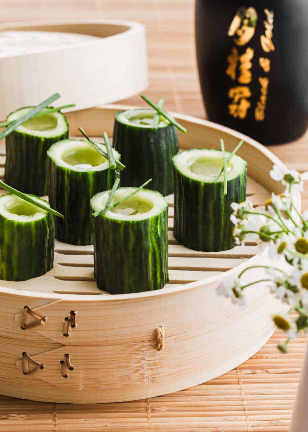 cucumber cups filled with saki and served on bamboo server.