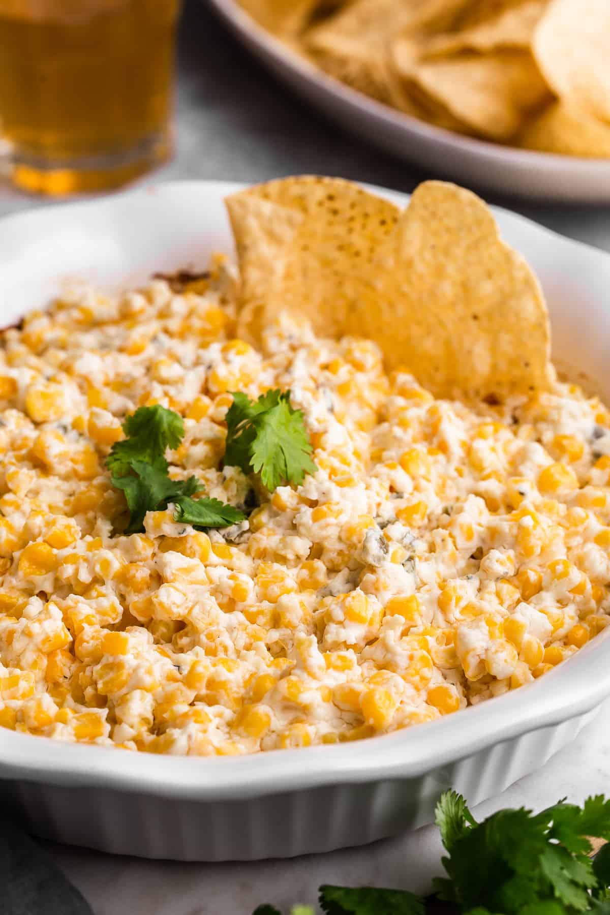 corn dip in white baking dish with tortilla chips inserted.