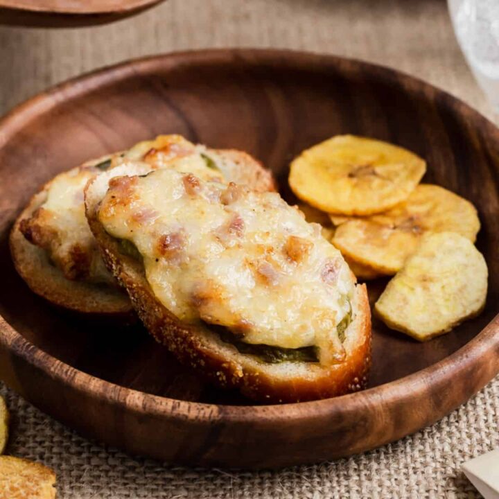 small wood plate with cheesy crostini appetizers on it.