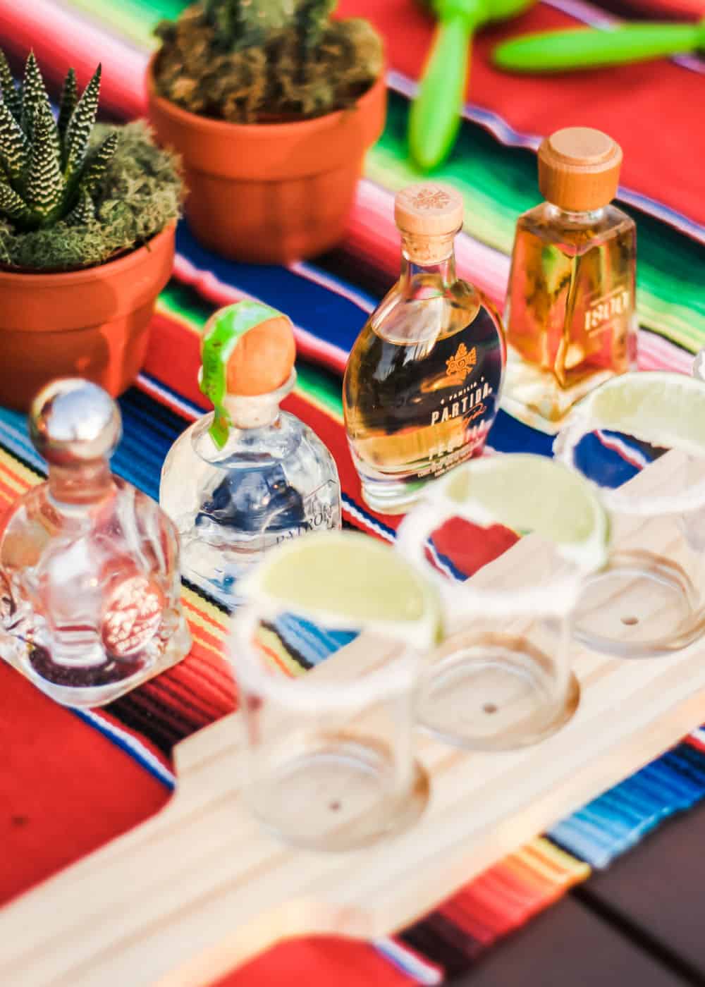 mini bottles of tequila with shot glasses lined up in a row.
