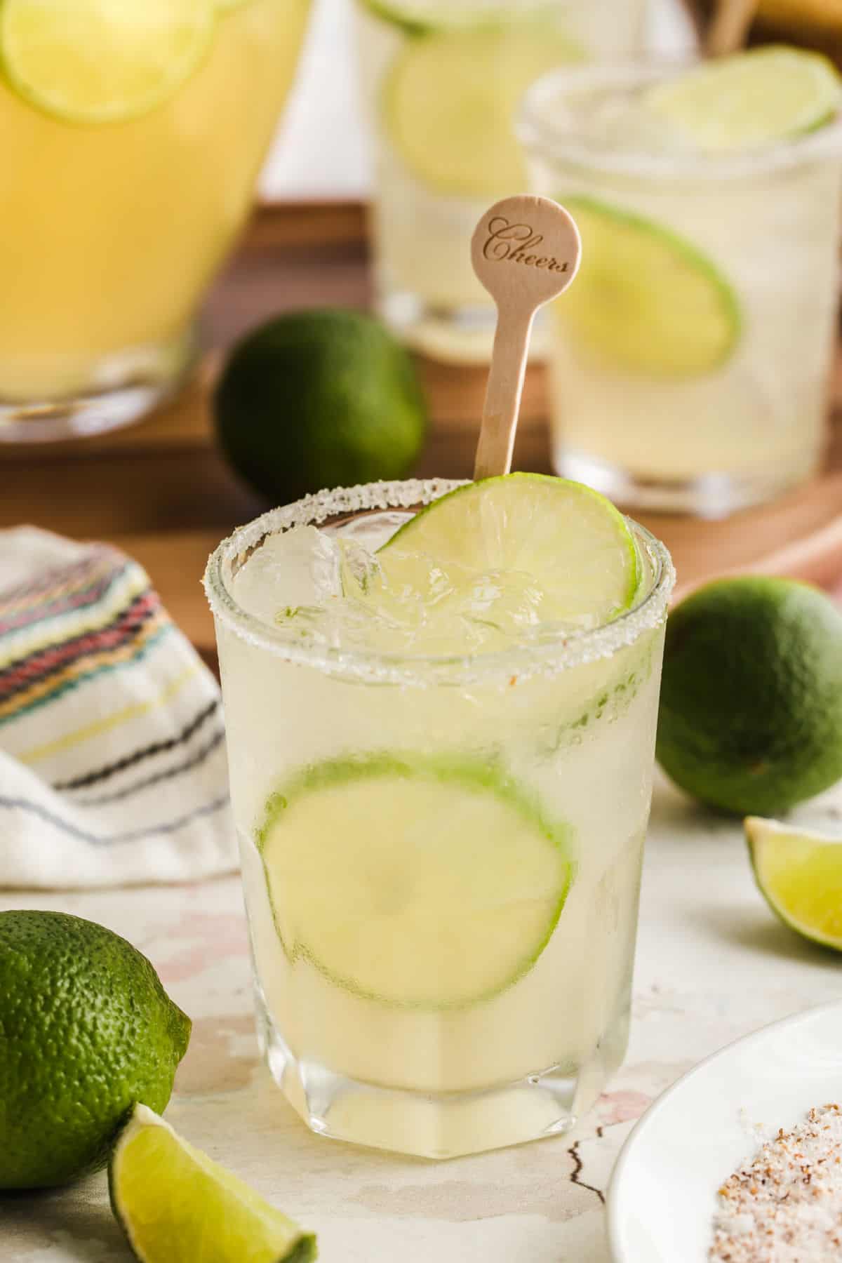 tumbler glass filled with margarita and lime wheels.