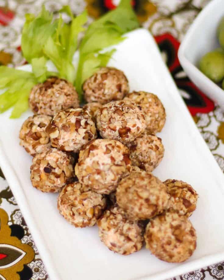 mini cheese balls placed in the shape of a grape cluster with celery leaves garnish.