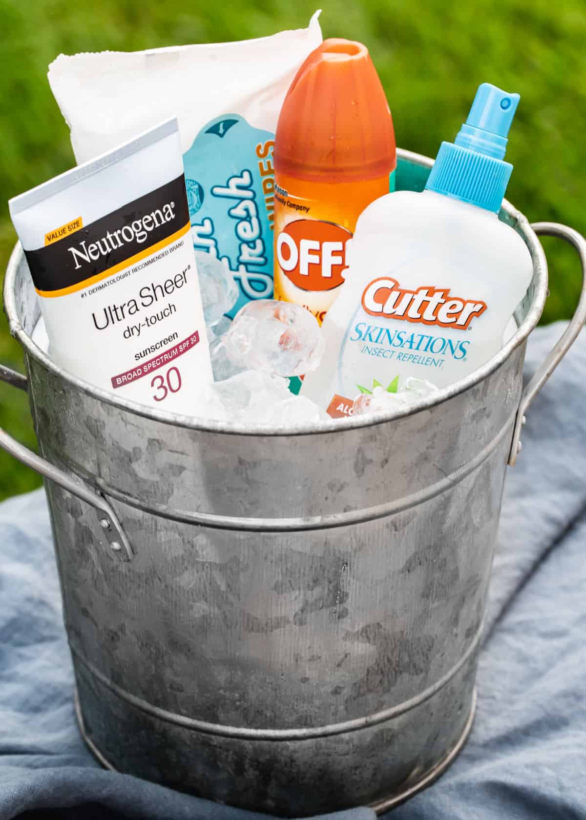 silver bucket filled with sunscreen and bug spray.