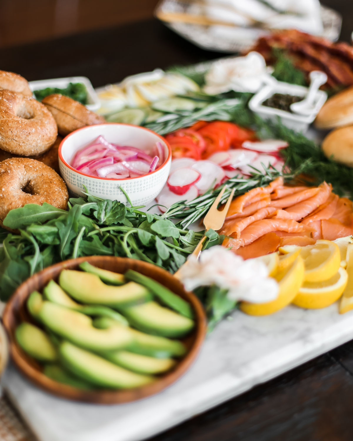 bagels and lox toppings on marble board.