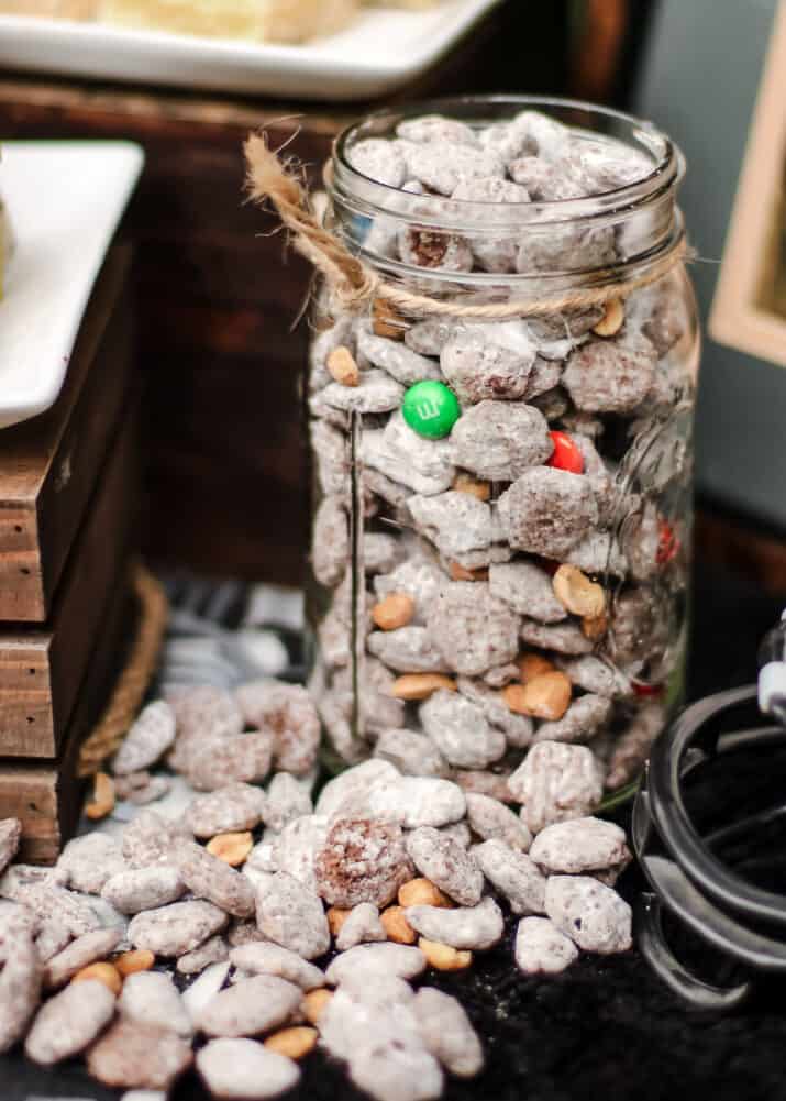 large mason jar filled with Chex mix muddy buddies with M&M's and peanuts.
