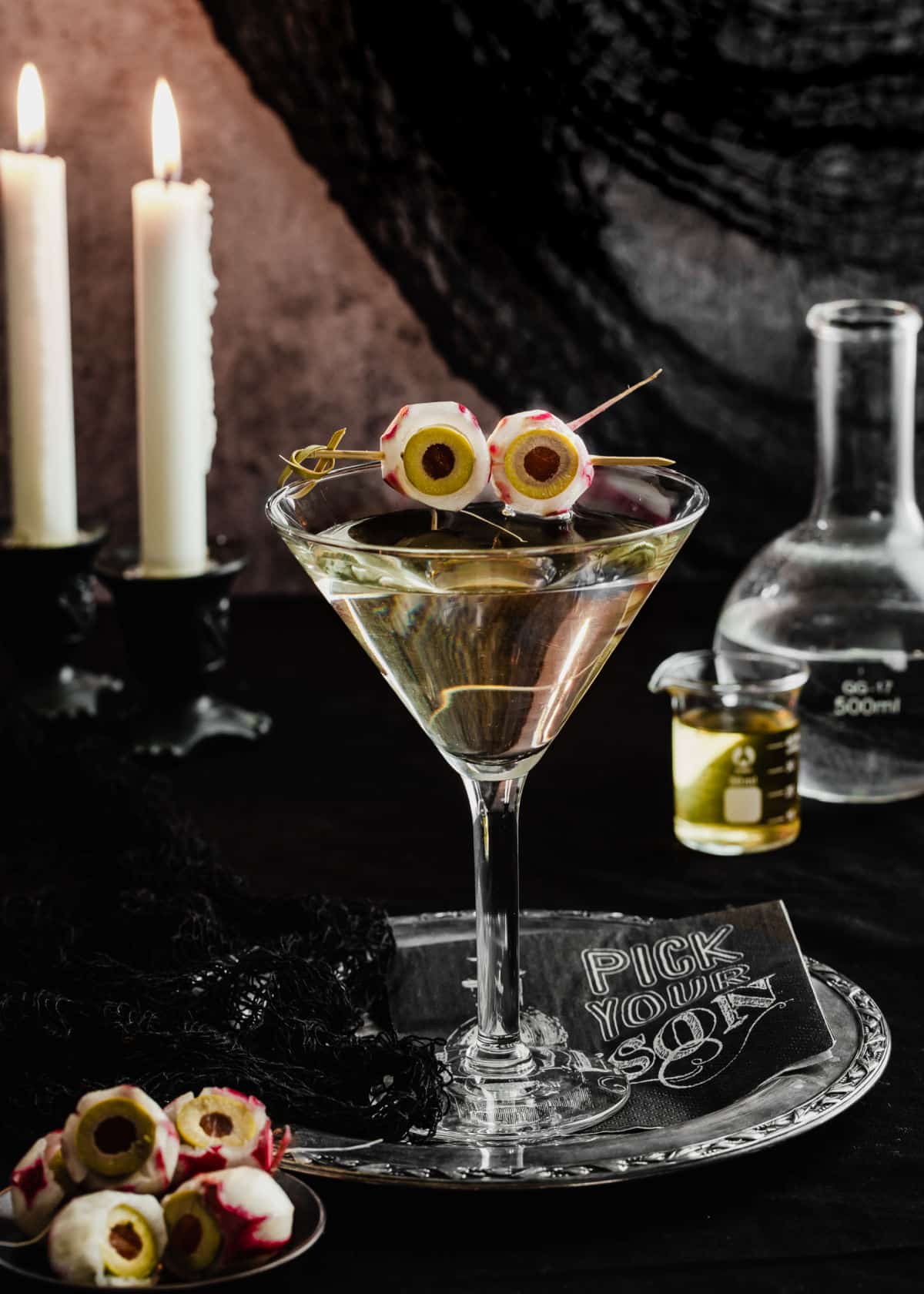 dirty martini in stem glass with radish and olive eyeballs for garnish.