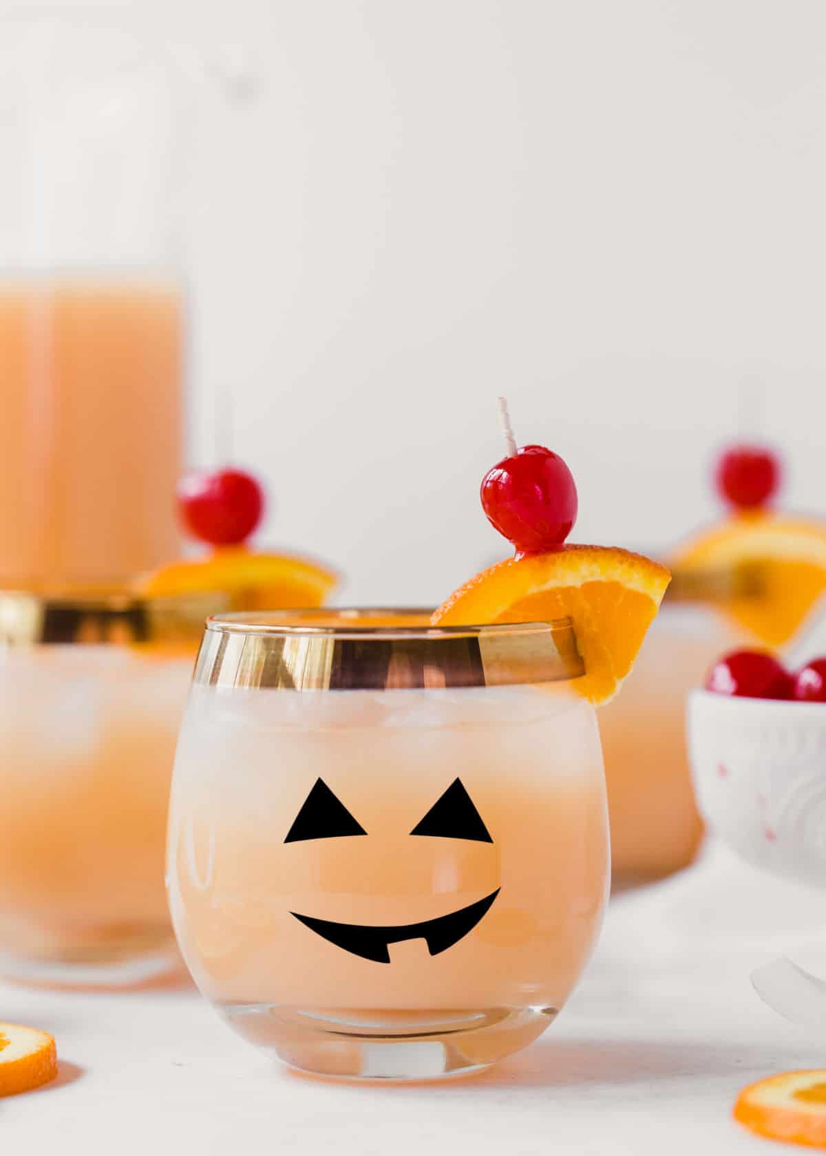 orange drink in round glass with jack-o-lantern face.
