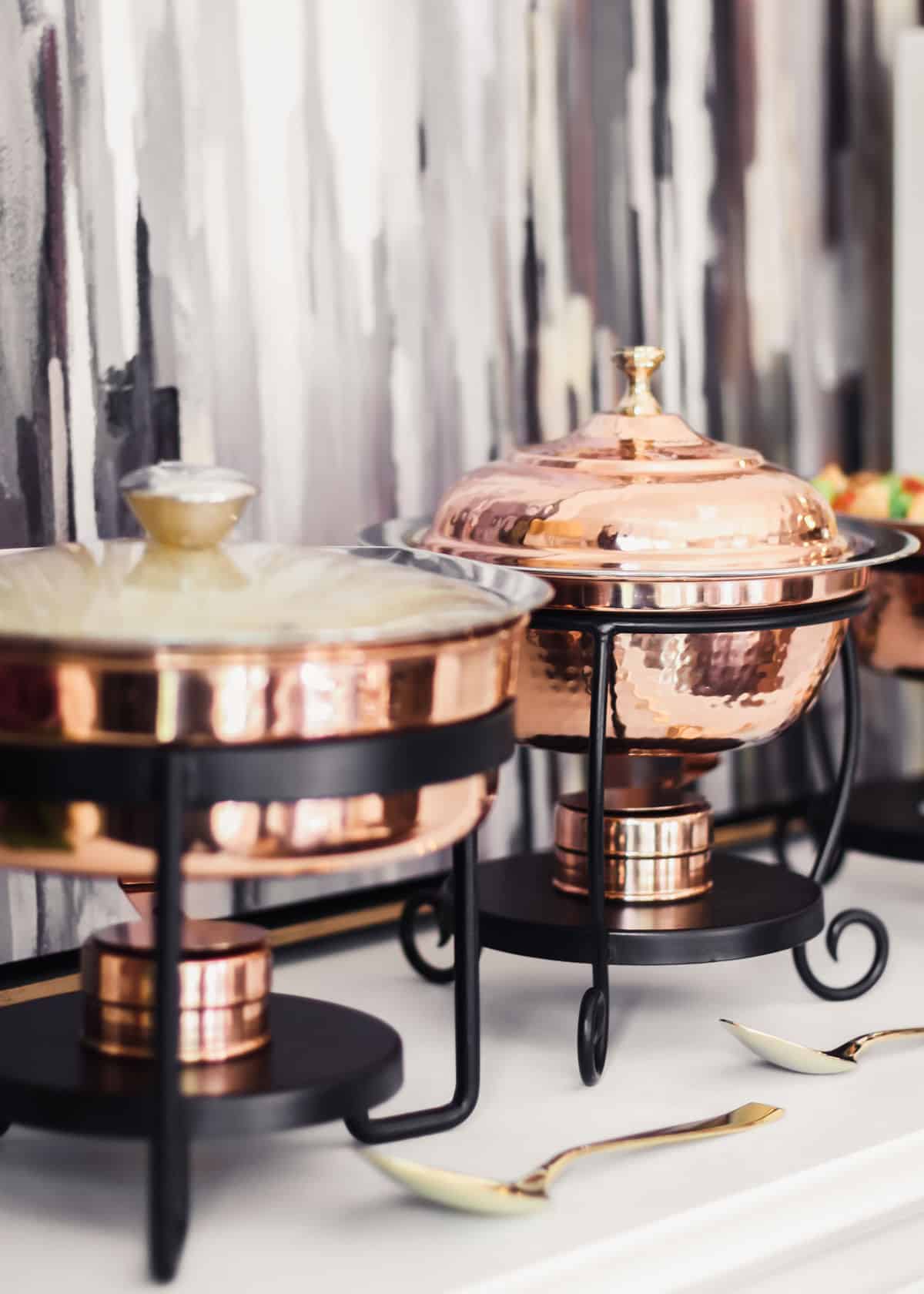 copper chafing dishes on white side board.