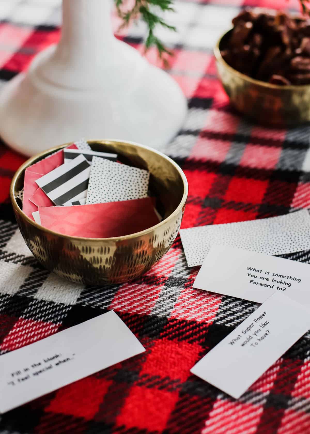 strips of paper with conversation questions printed on them, sitting on red plaid tablecloth.
