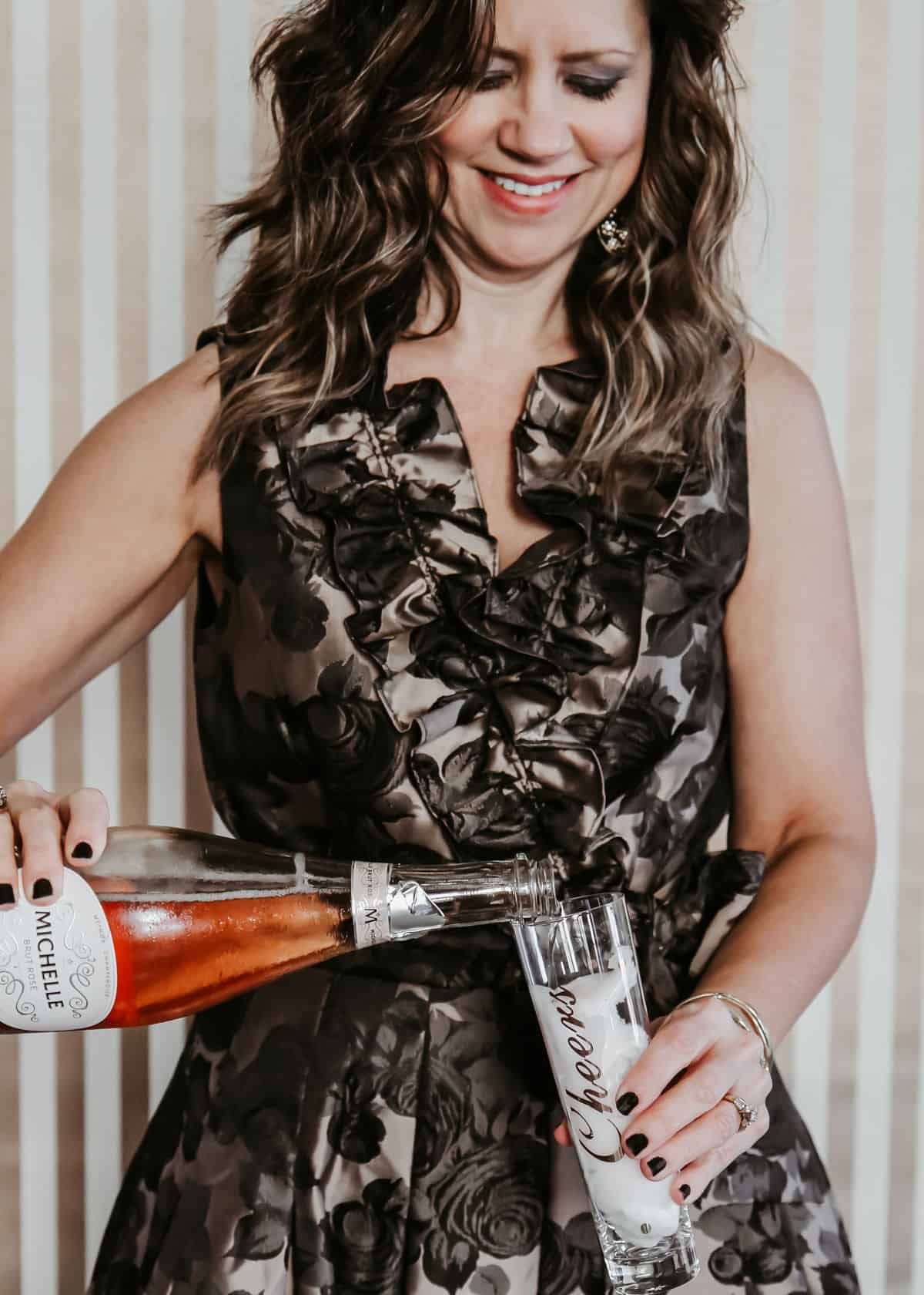 lady in a cocktail dress pouring champagne into a glass.