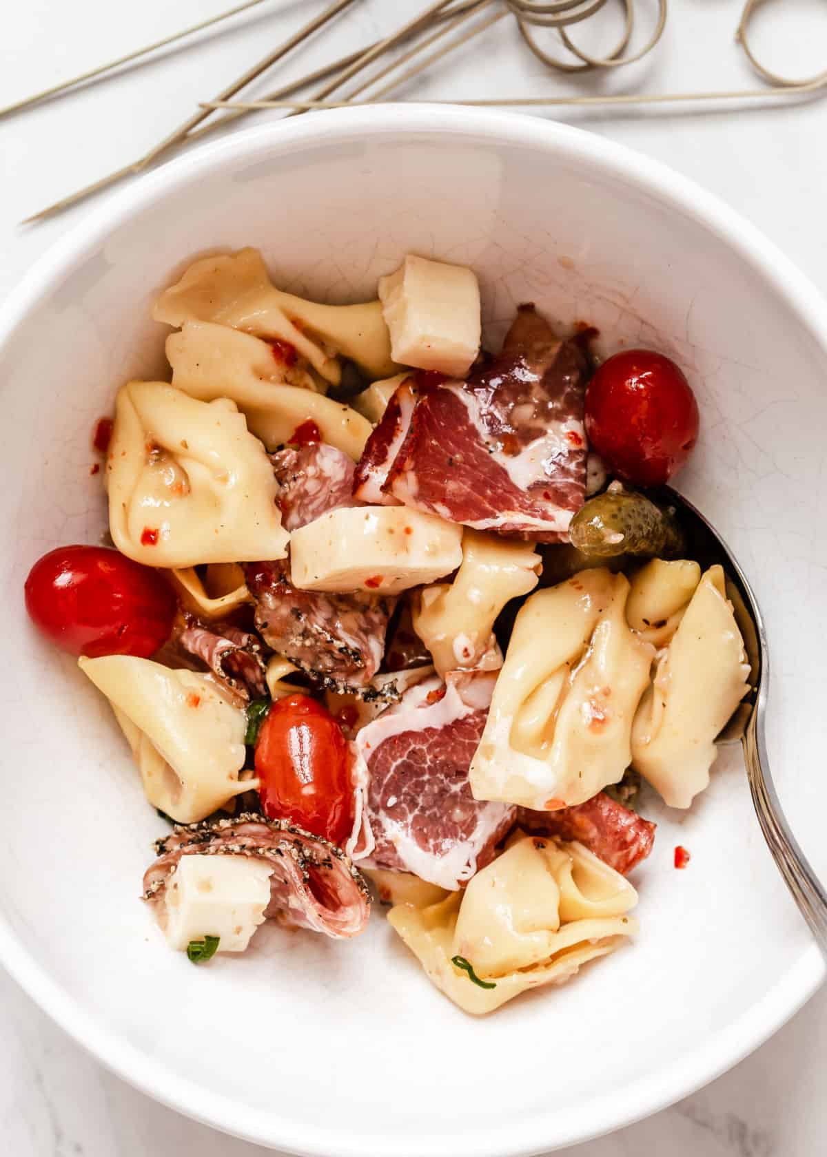 antipasto ingredients in white bowl with Italian dressing marinade.