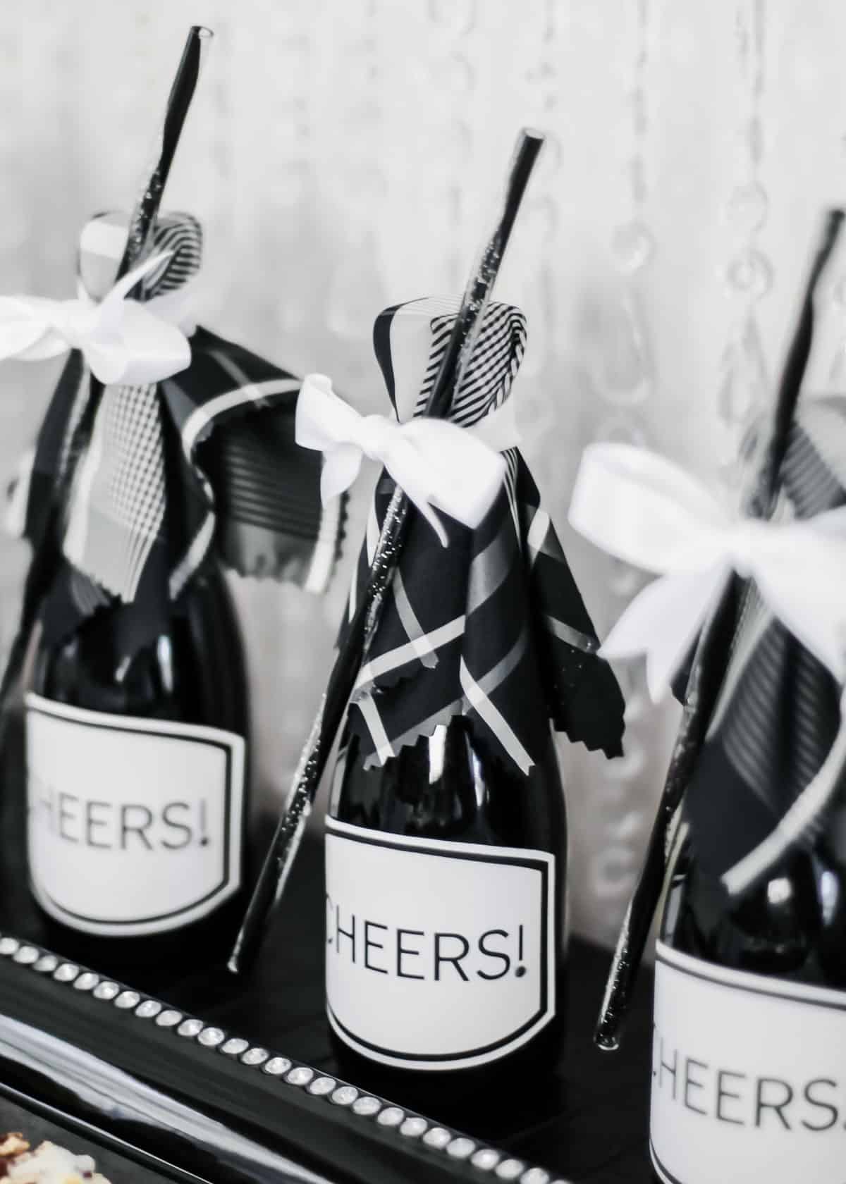 mini bottles of champagne dressed up for a party with straws tied on with ribbon.