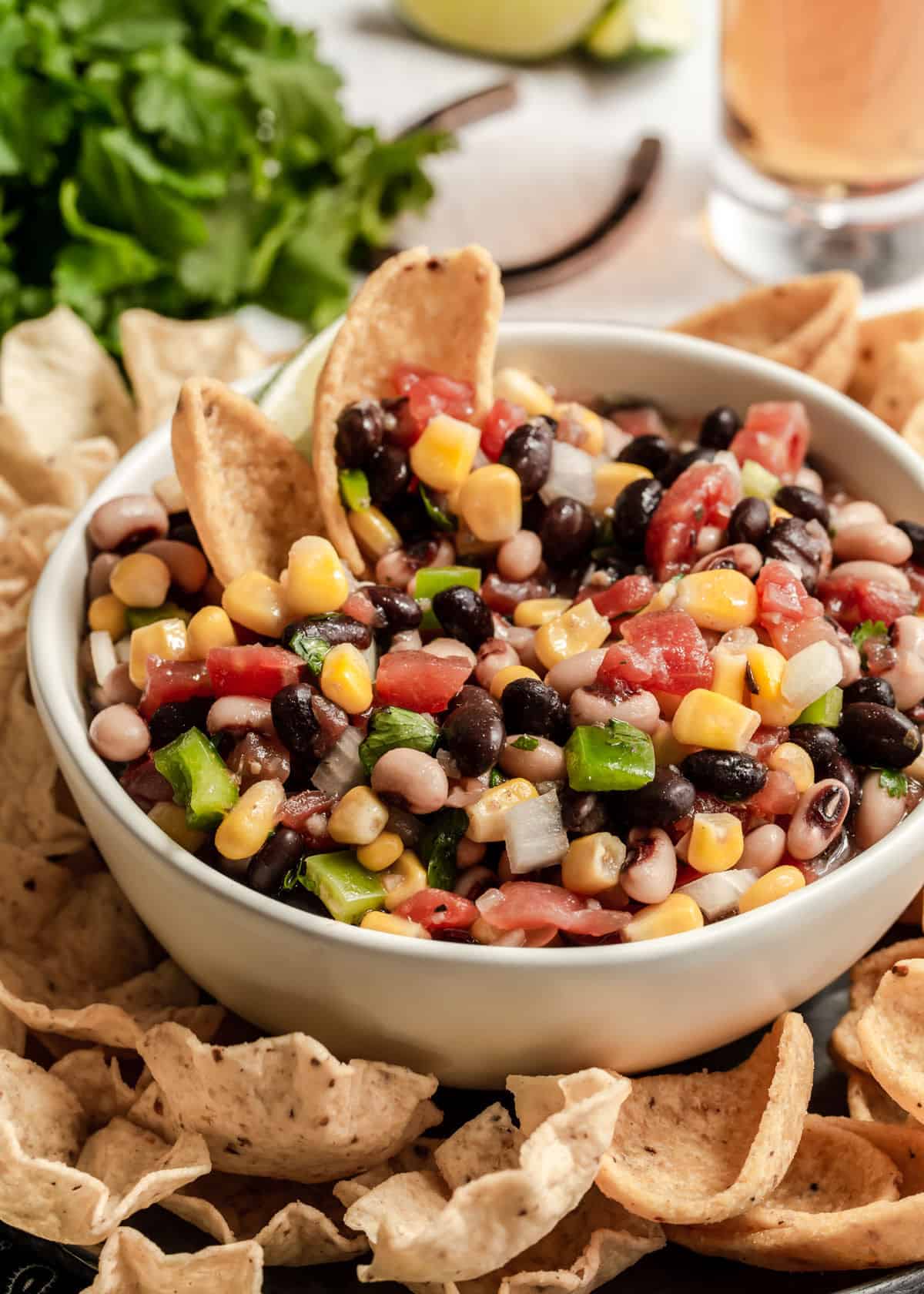 bean and corn salsa dip in cream bowl surrounded by corn chips.