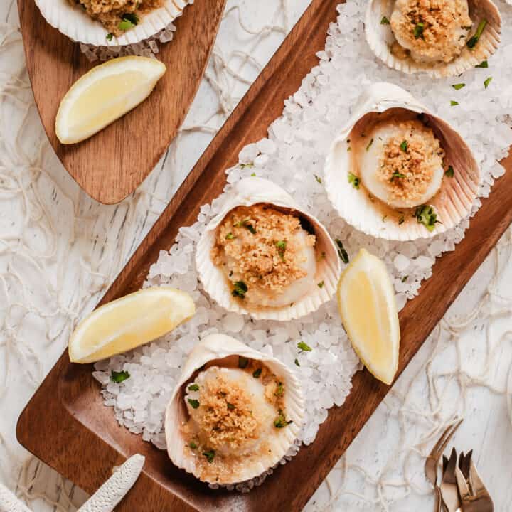 overhead view of long wood trays topped with scallops in shells on a bed of rock salt.