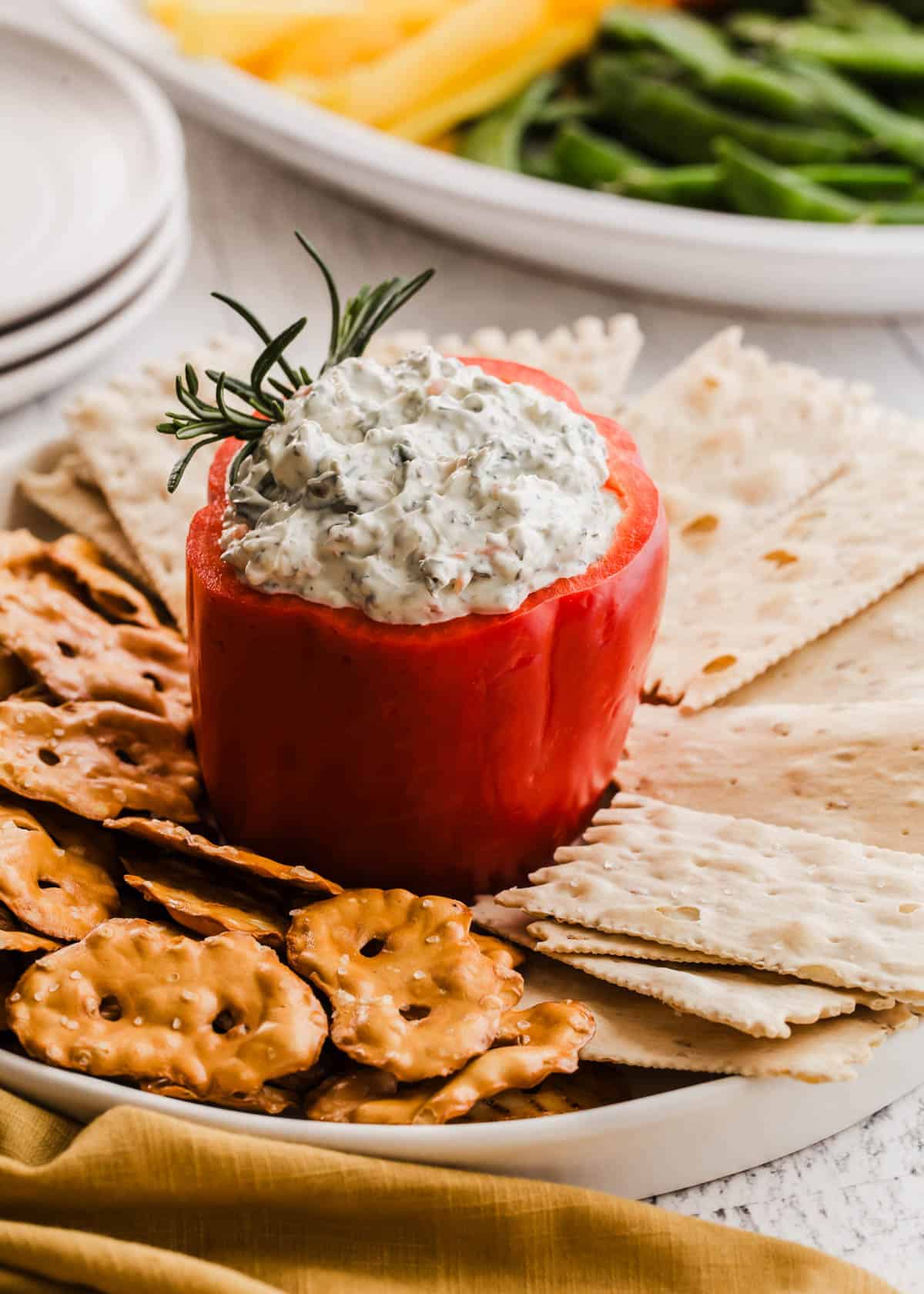 spinach dip inside a red pepper with crackers around it.