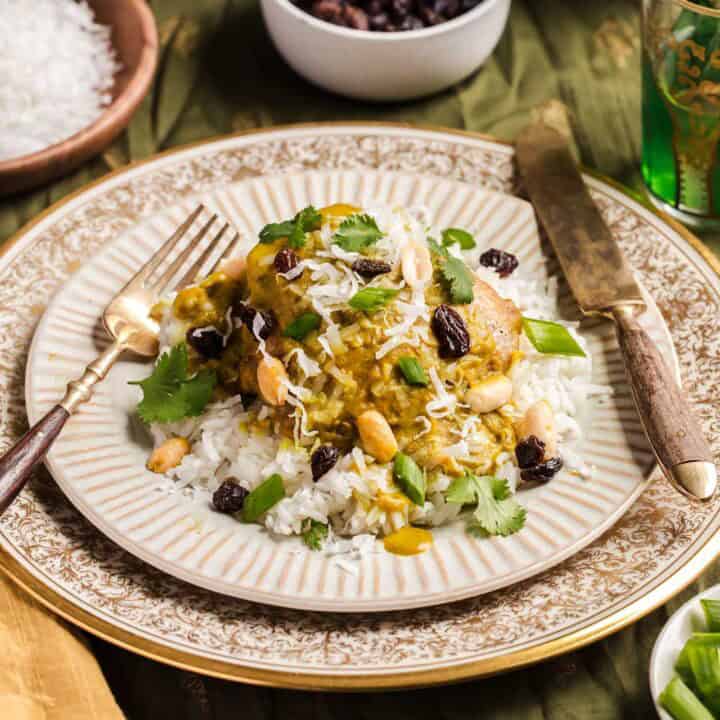 curry chicken with rice served on gold trimmed plate.
