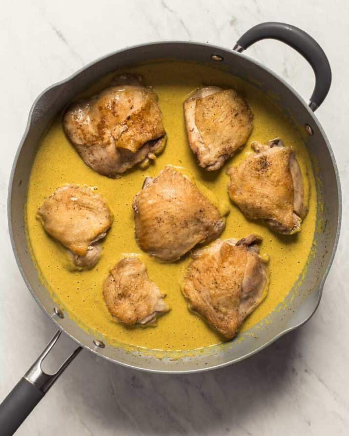 cooked chicken thighs in curry sauce in large skillet.