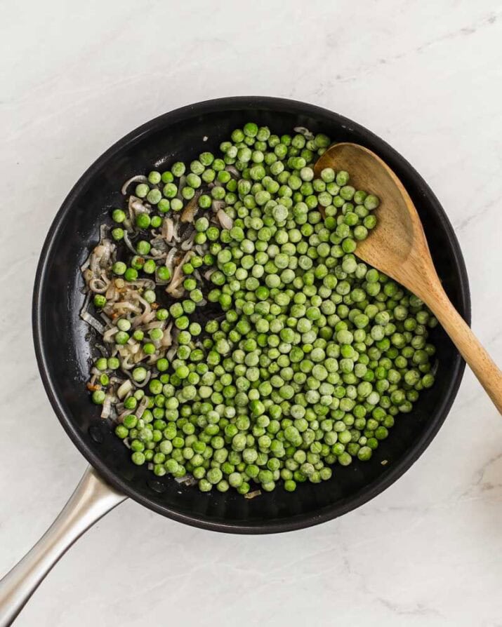 frozen green peas in large skillet with cooked shallots.