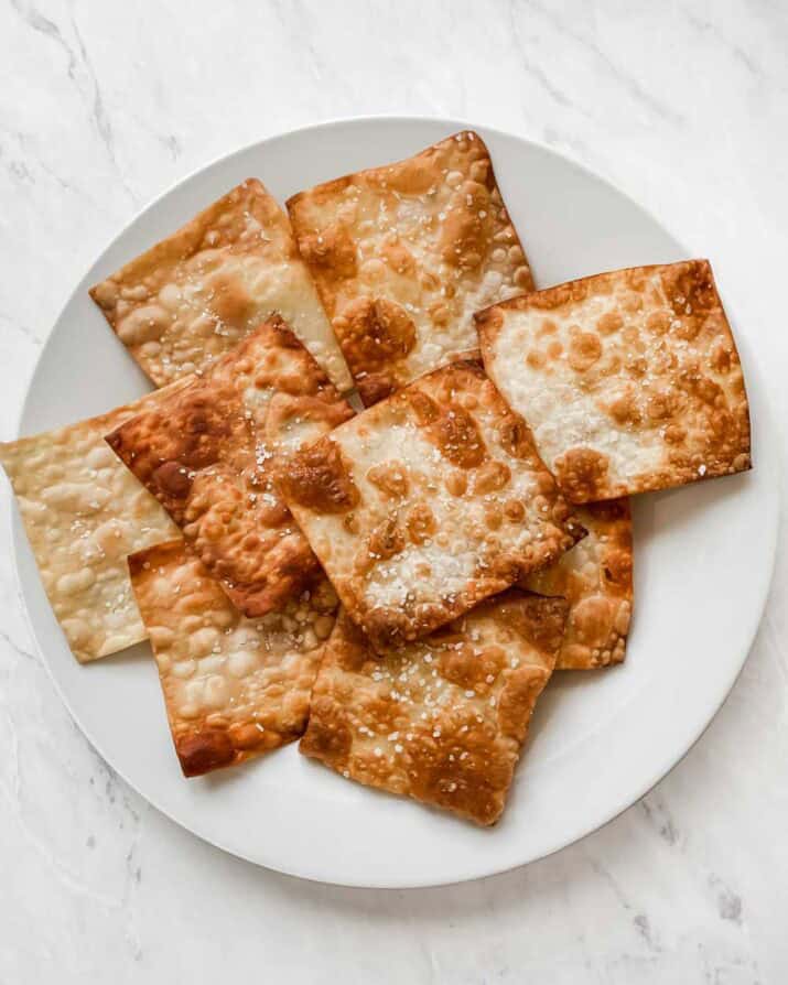 fried wonton wraps piled on a white plate.