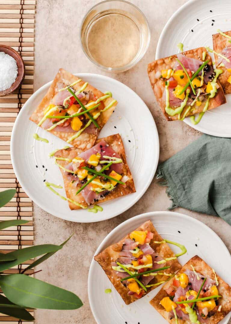 three small plates with smoked ahi tuna on fried wontons, with fruit salsa on top.
