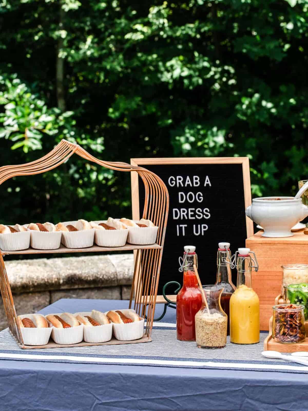 party table with hot dogs on wire stand and hot dog sign