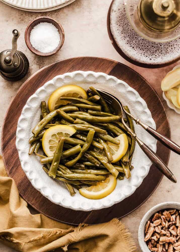 green beans with lemon slices served in white bowl on dining table.