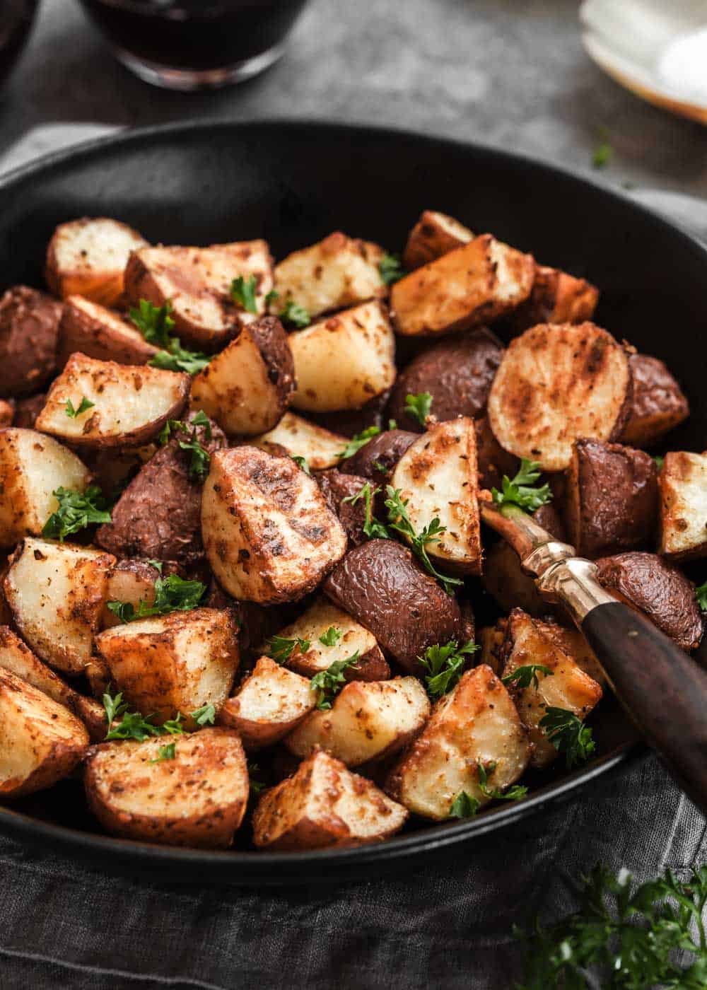 close up of roasted potatoes in black serving bowl.
